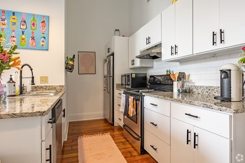 A kitchen with white cabinets and granite countertops.