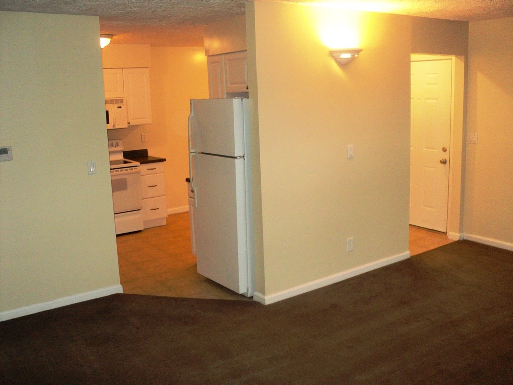 A white refrigerator in a kitchen with a stove and cabinets.