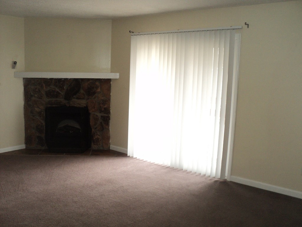 A room with a fireplace and a window with white curtains.