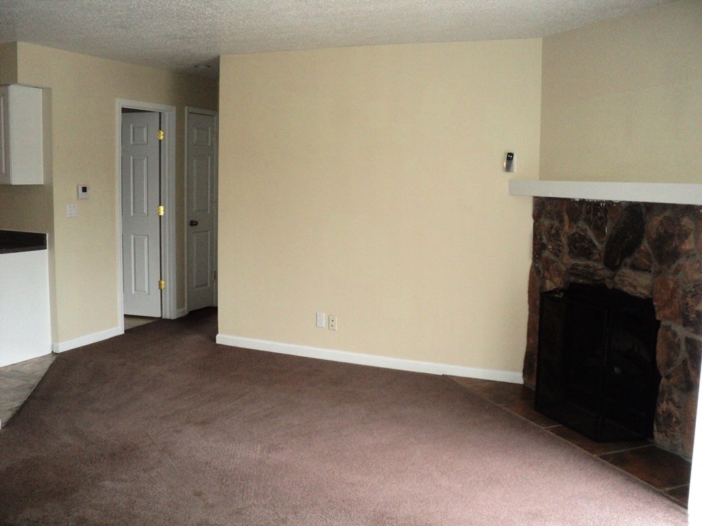 A living room with a fireplace and carpeted floor.