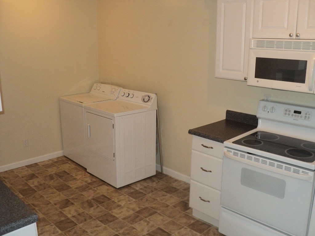 A white dishwasher is next to a white oven in a kitchen.