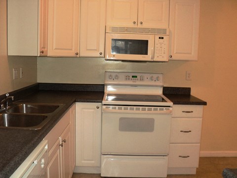 A white oven and microwave above a white stove in a kitchen.