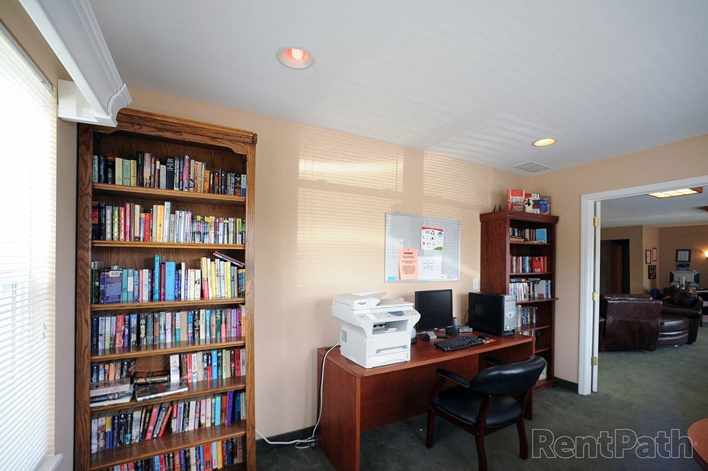 a home office with a desk and a bookcase with a printer and a computer