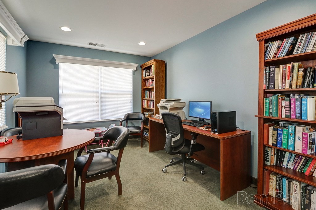 a library with a desk with a computer and bookshelves