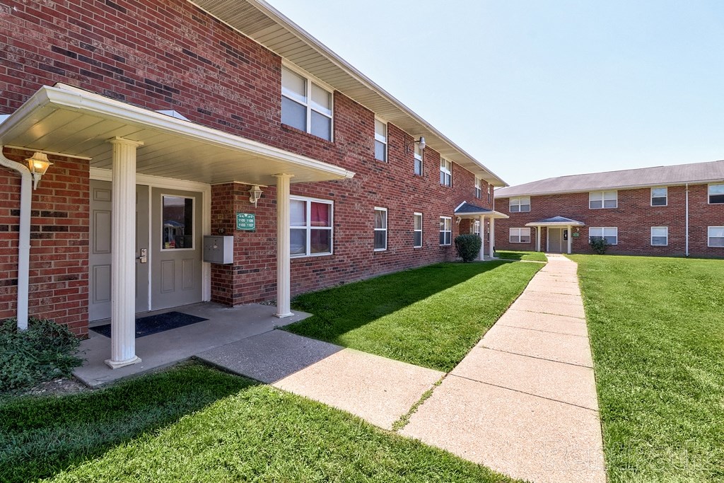 a sidewalk in front of a brick building with grass