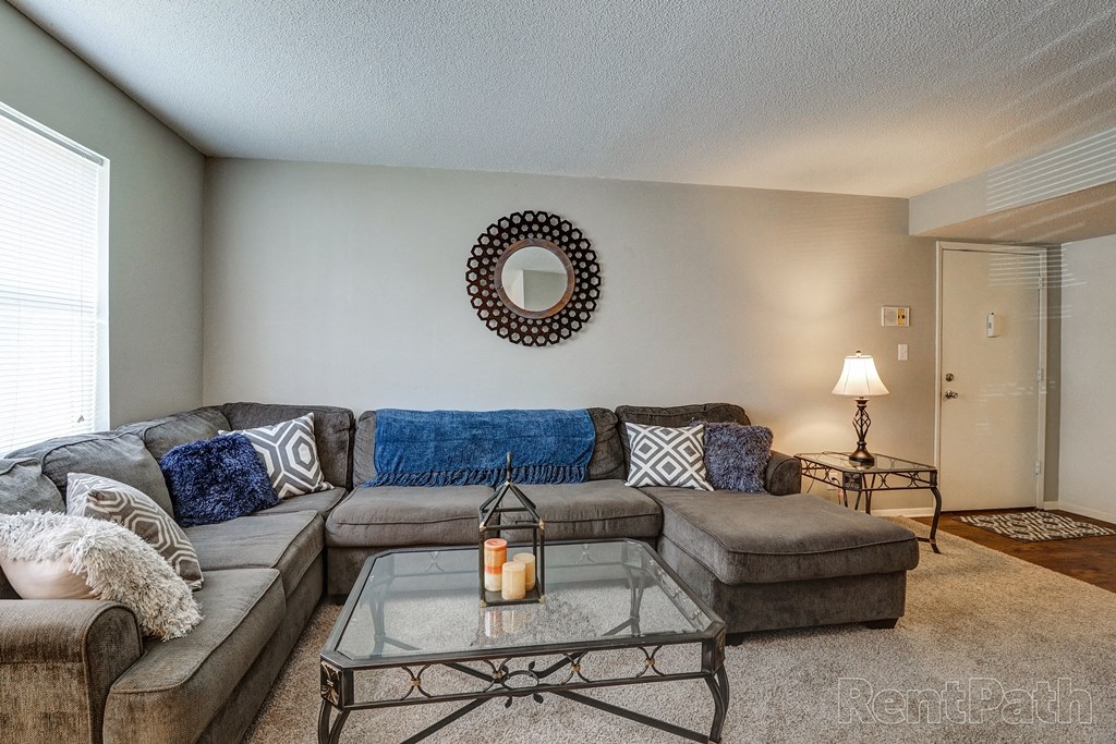 the living room has a large couch and a glass coffee table