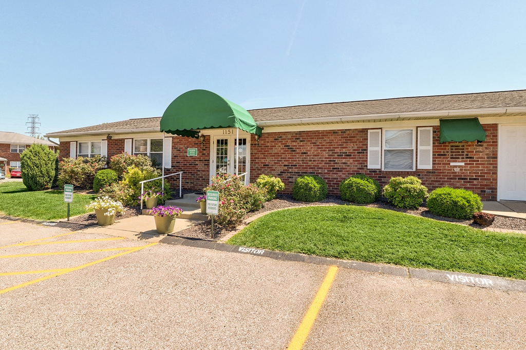 a brick building with a green roof and a driveway