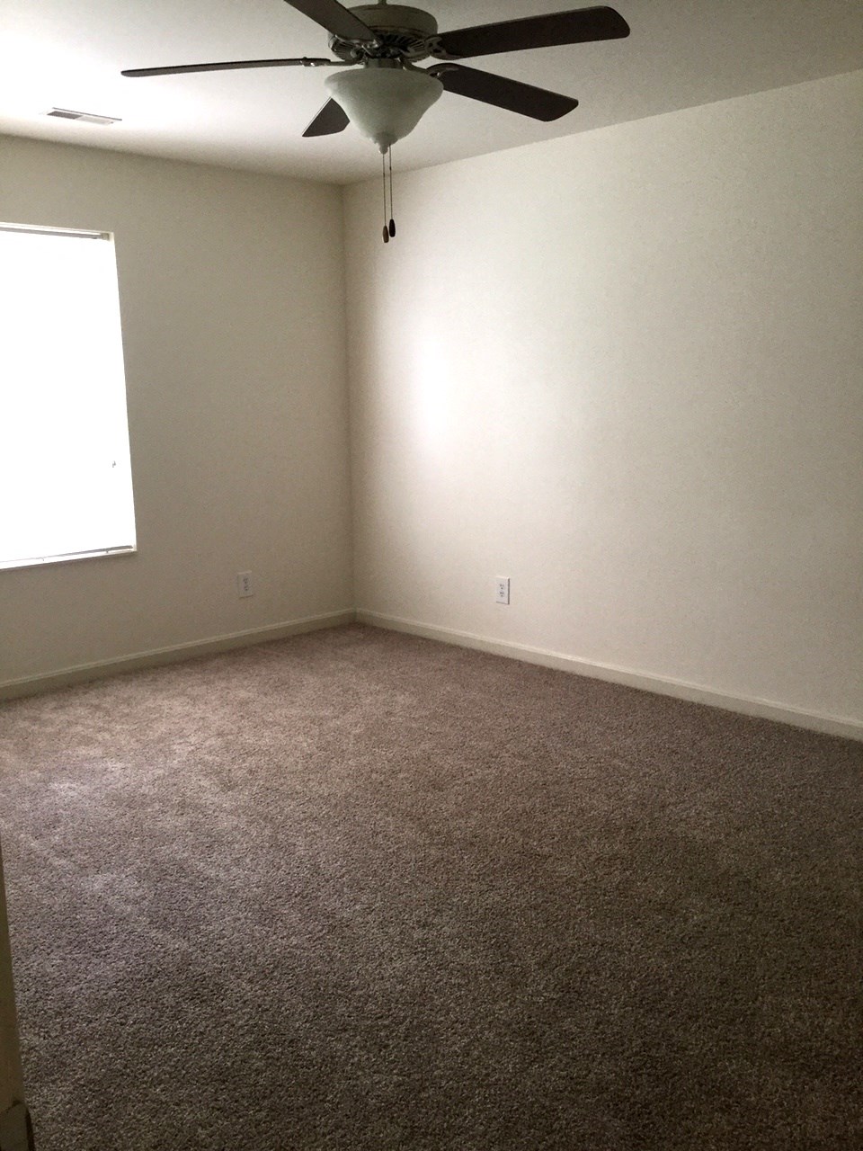 an empty room with a ceiling fan and a window