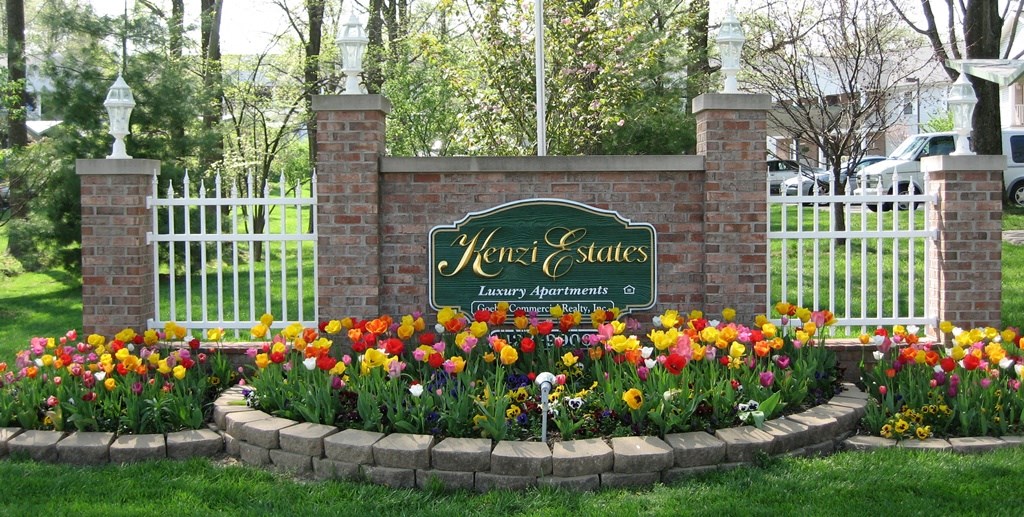 a garden with flowers and a sign in front of a fence