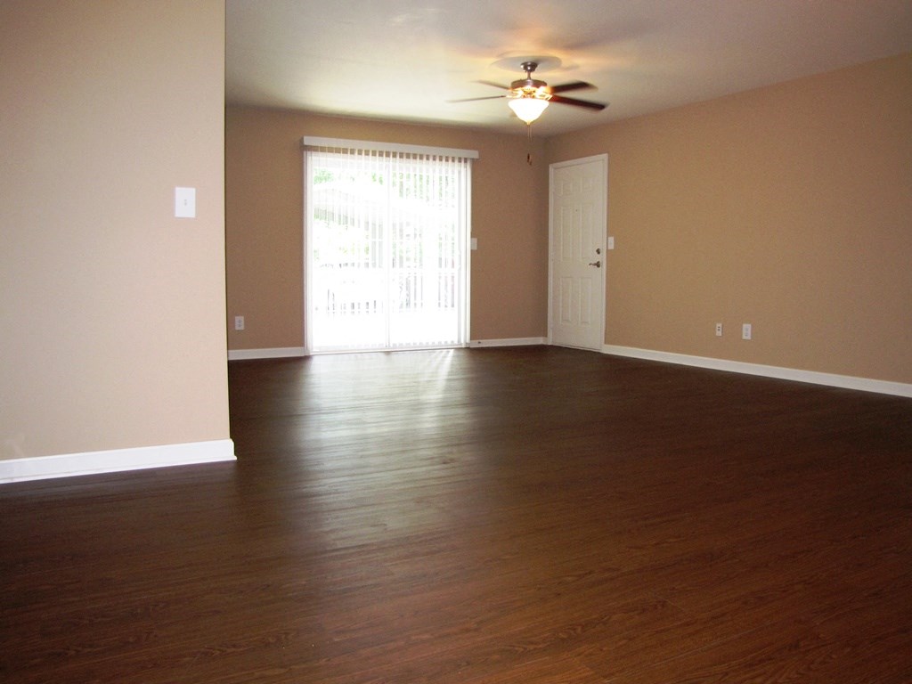 an empty living room with wood floors and a ceiling fan