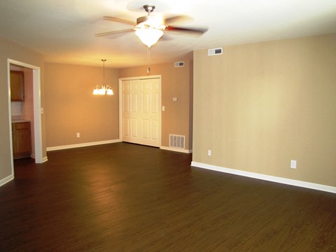 an empty living room with wood floors and a ceiling fan