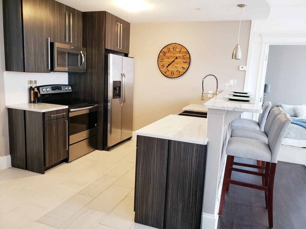 a kitchen with stainless steel appliances and a counter with a kitchen island and a clock