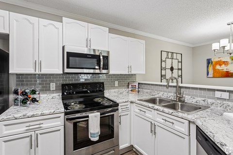 A kitchen with white cabinets and a black stove top.
