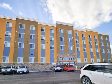 A large multi-story building with a parking lot in front.