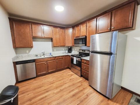 A kitchen with wooden cabinets and a stainless steel refrigerator.