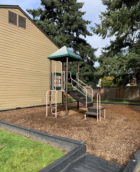 A playground with a green roof and a slide.