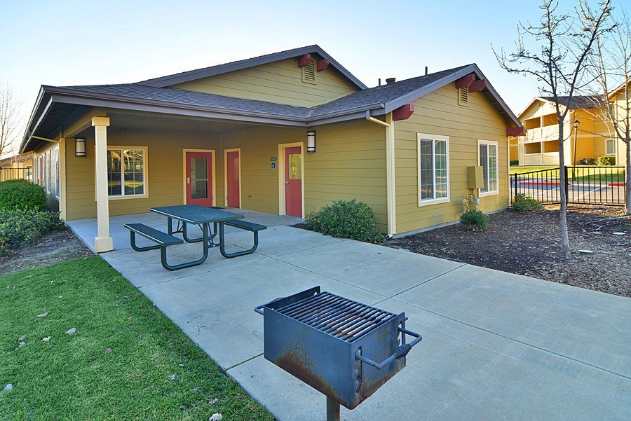 A yellow house with a red door and a picnic table in front.