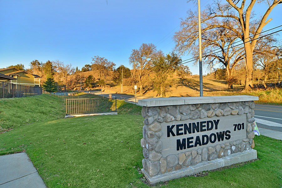 A stone sign that says Kennedy Meadows stands in a grassy area.