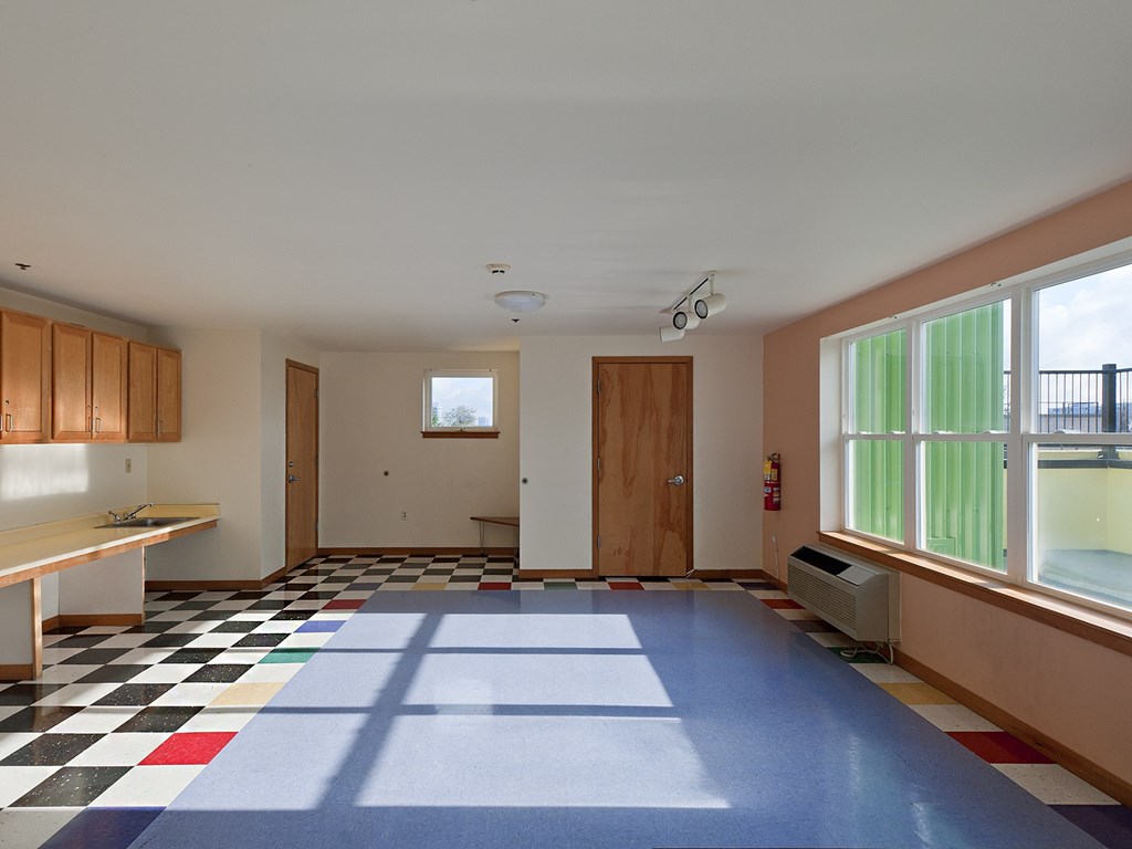 A room with a checkered floor and a window with green curtains.
