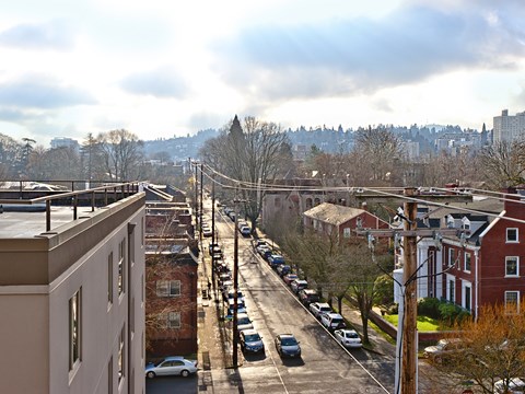 A street view of a residential area with houses and parked cars.