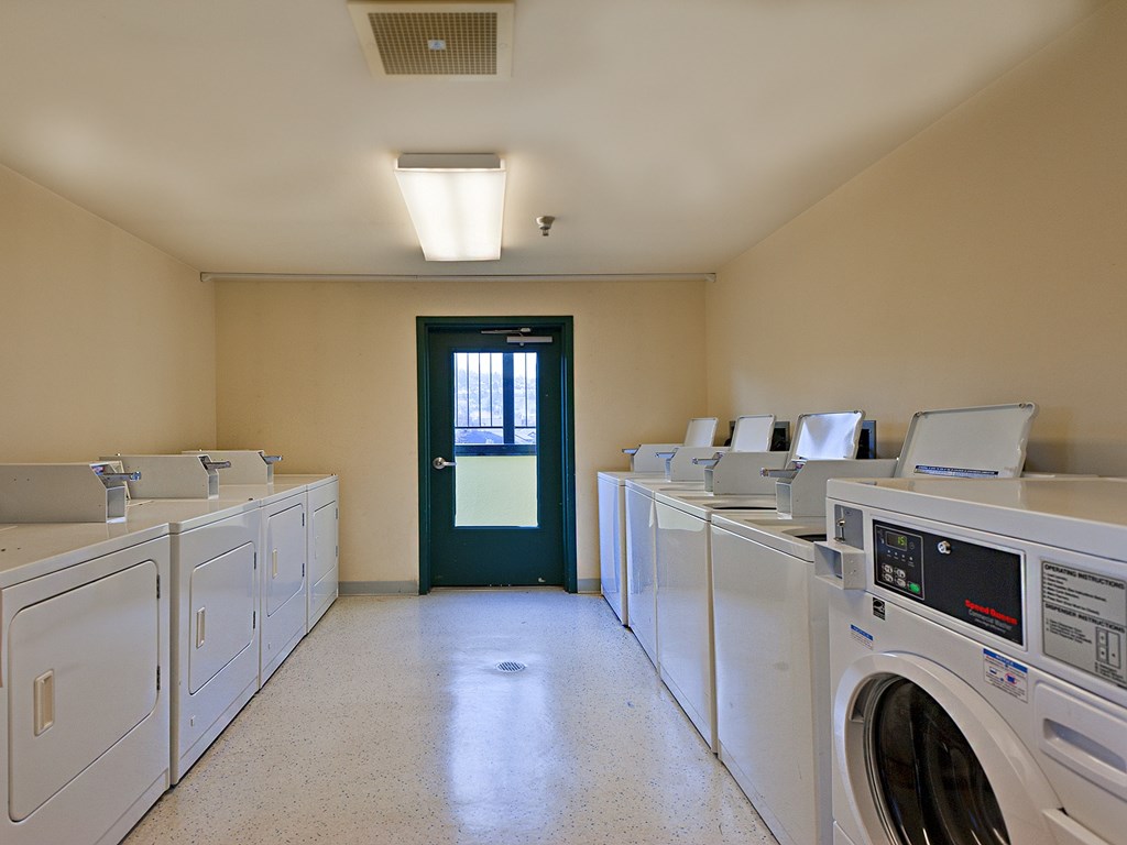 A laundry room with a row of washers and dryers.