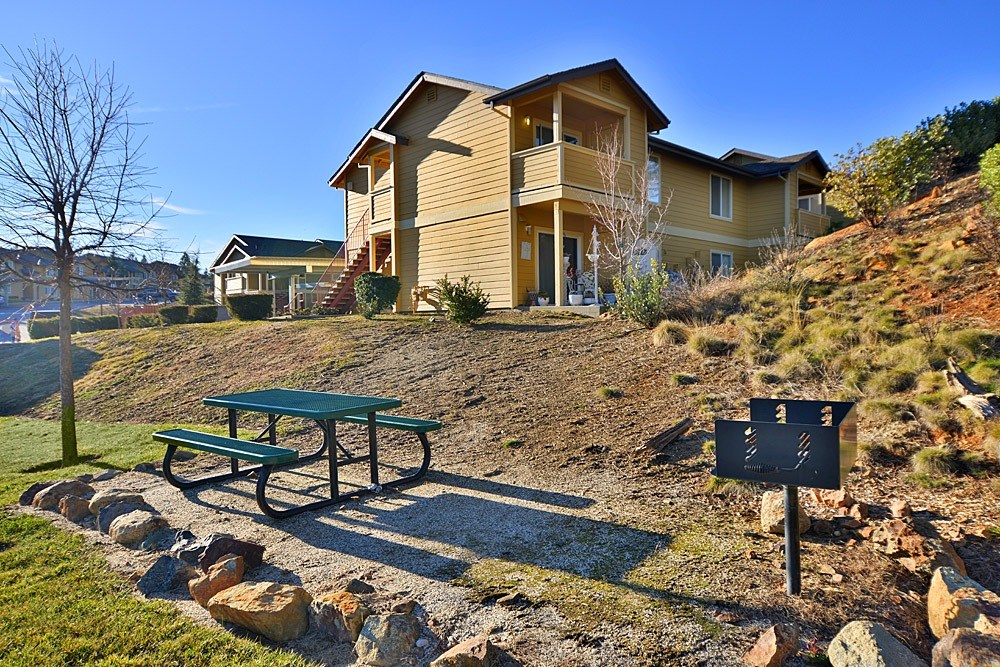 A house with a green picnic table in front of it.