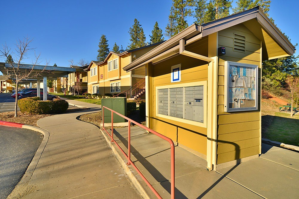 A small yellow building with a red railing in front of it.