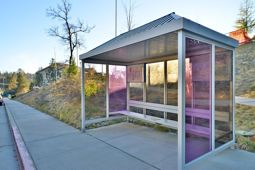 A bus stop with a purple tint on the windows.