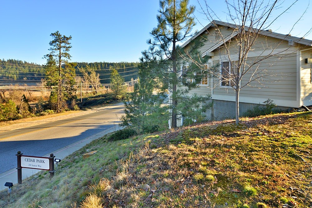 A house is situated on a hill with a sign that says Cedar Park in front of it.