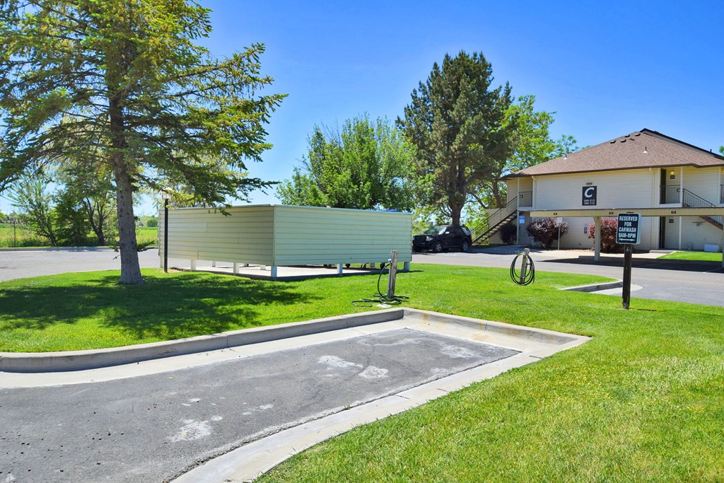 A green and white building sits next to a tree and a parking lot.