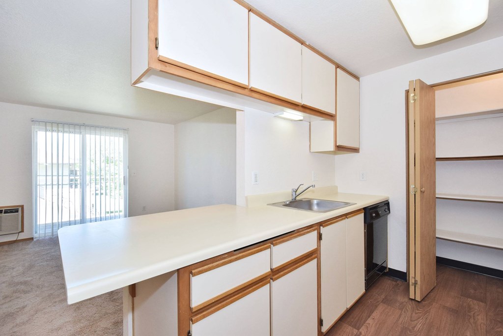 A kitchen with white countertops and wooden cabinets.