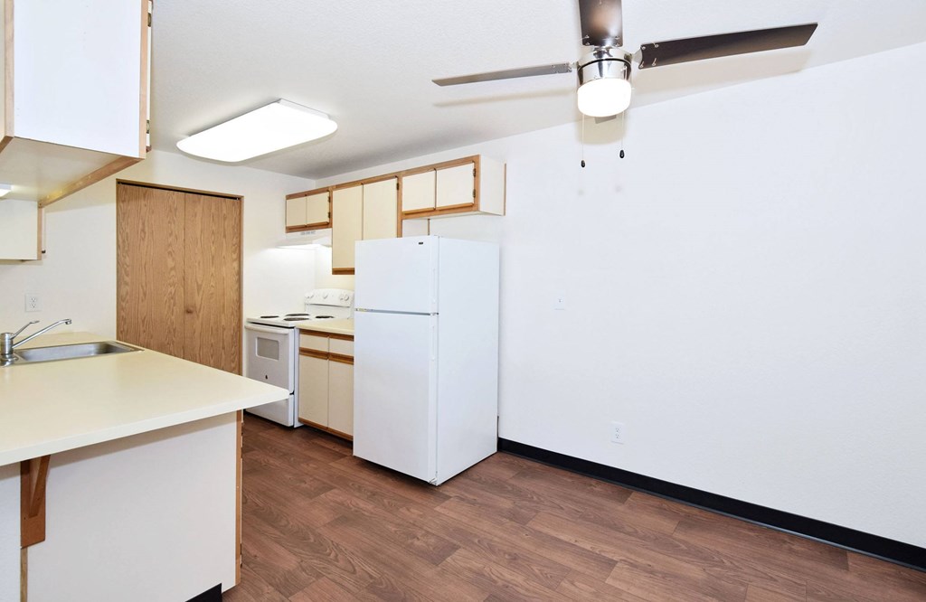 A kitchen with white appliances and wooden cabinets.