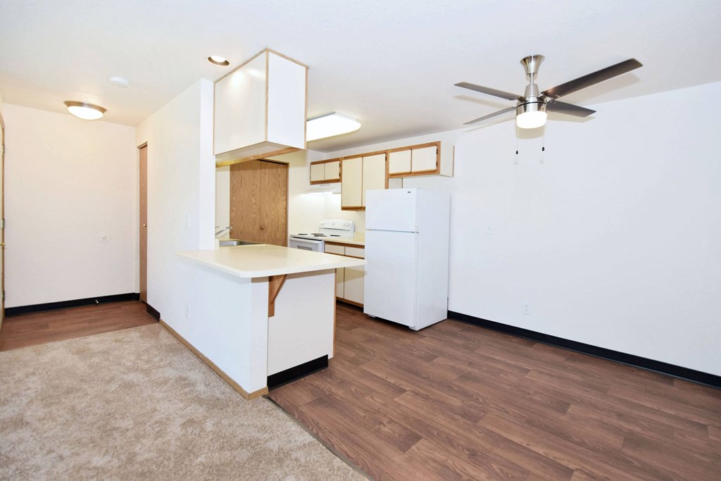 A kitchen with white appliances and wooden floors.
