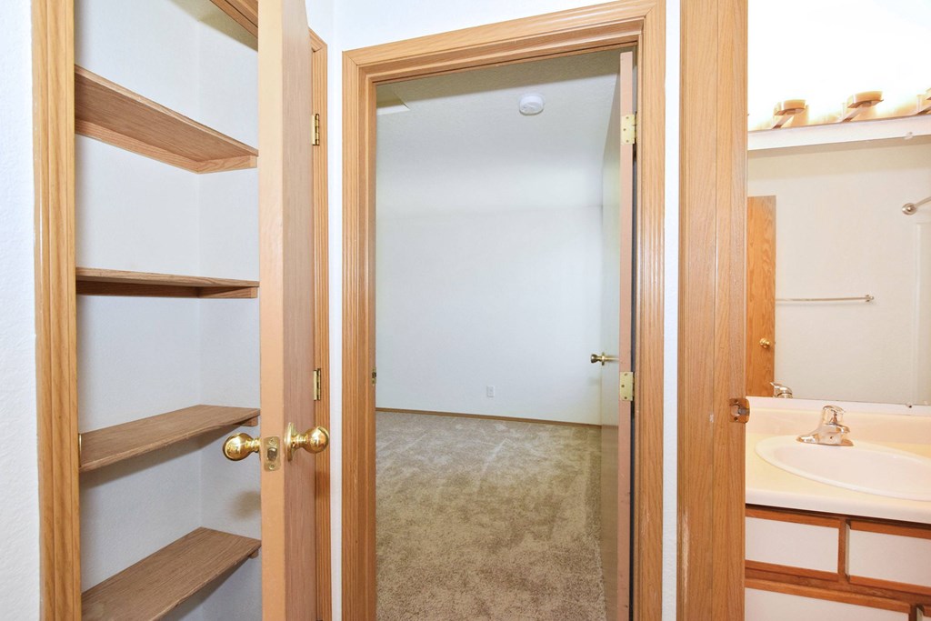 A bathroom with a sink, mirror, and a door that opens to a hallway.
