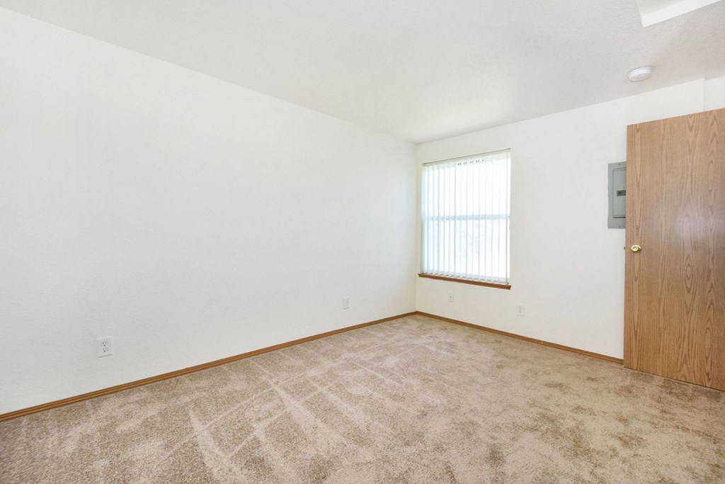 A room with a carpeted floor and a door on the right side.