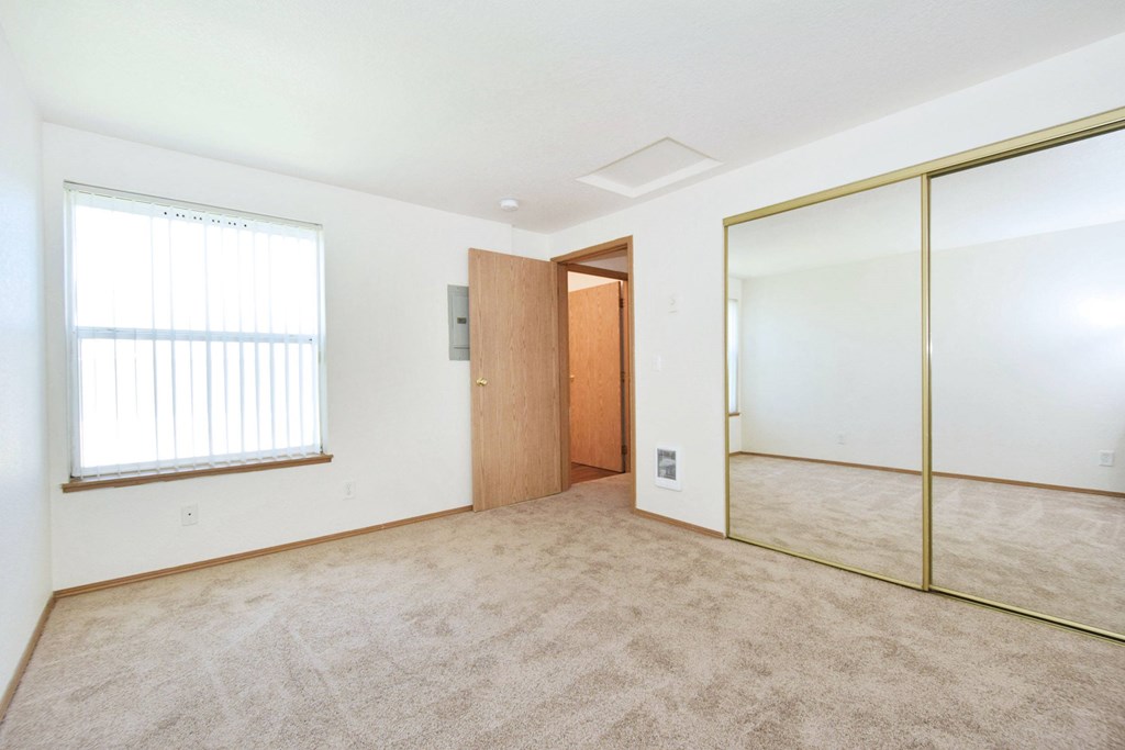 A room with a carpeted floor, a wooden door, and a glass partition wall.