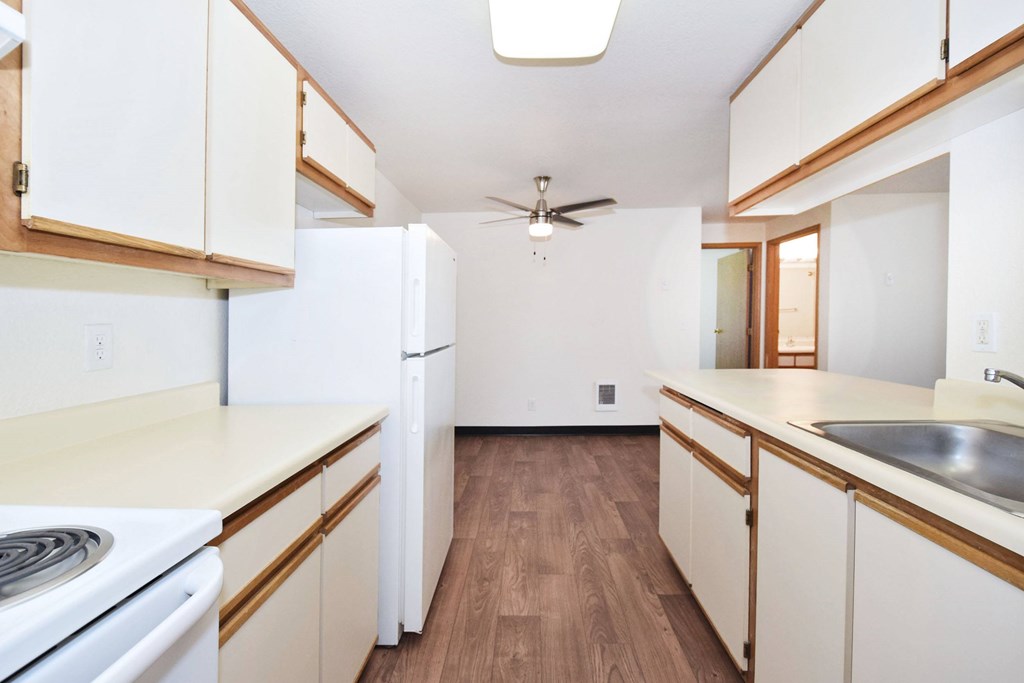 A kitchen with white appliances and wooden cabinets.