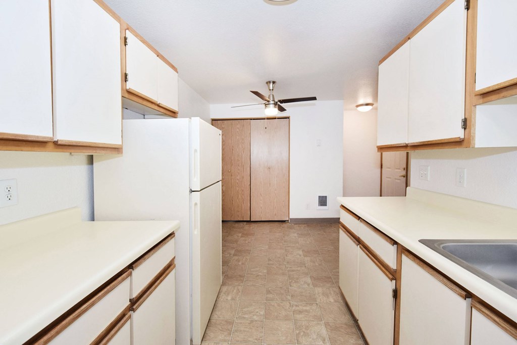 A kitchen with white cabinets and a fan.