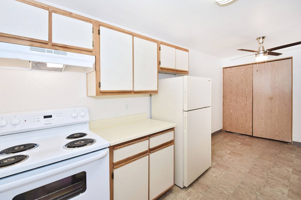 A kitchen with a white stove and white cabinets.