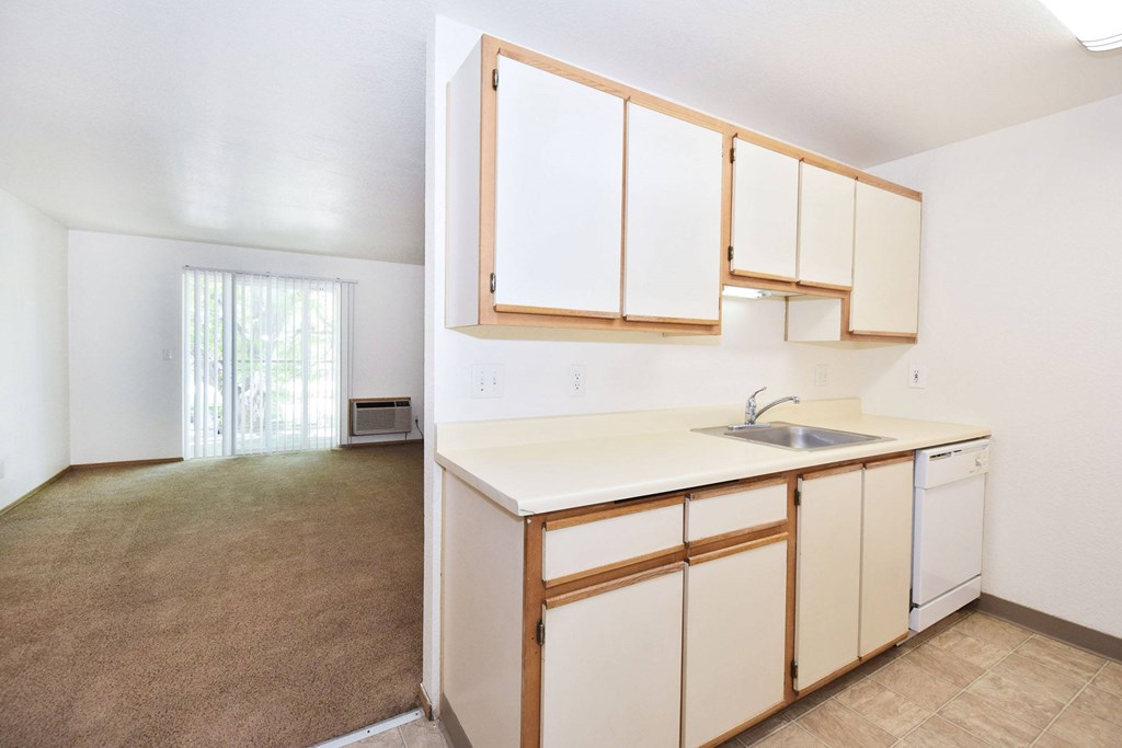 A kitchen with white countertops and wooden cabinets.