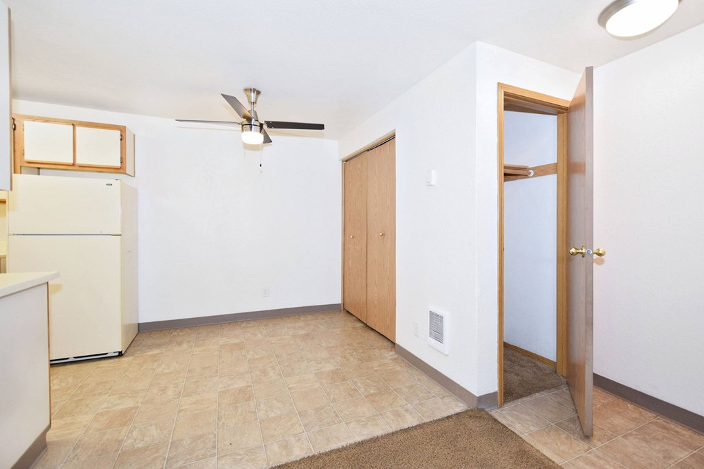 A room with a ceiling fan and a door leading to another room.