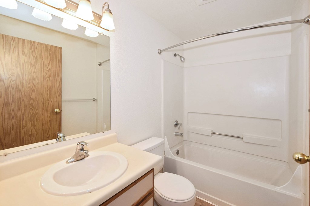 A white bathroom with a toilet, sink, and bathtub.
