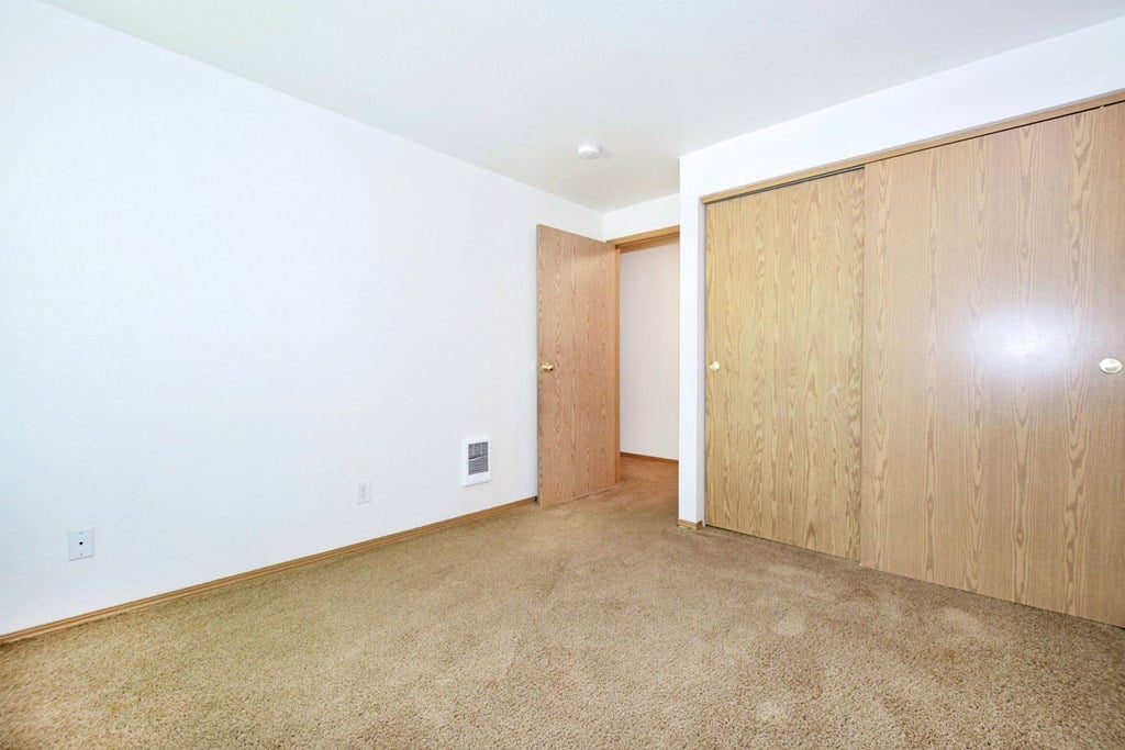 A room with a carpeted floor and a wooden door.