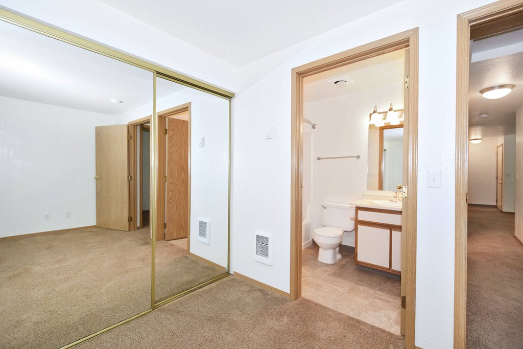 A bathroom with a toilet, sink, and mirror.