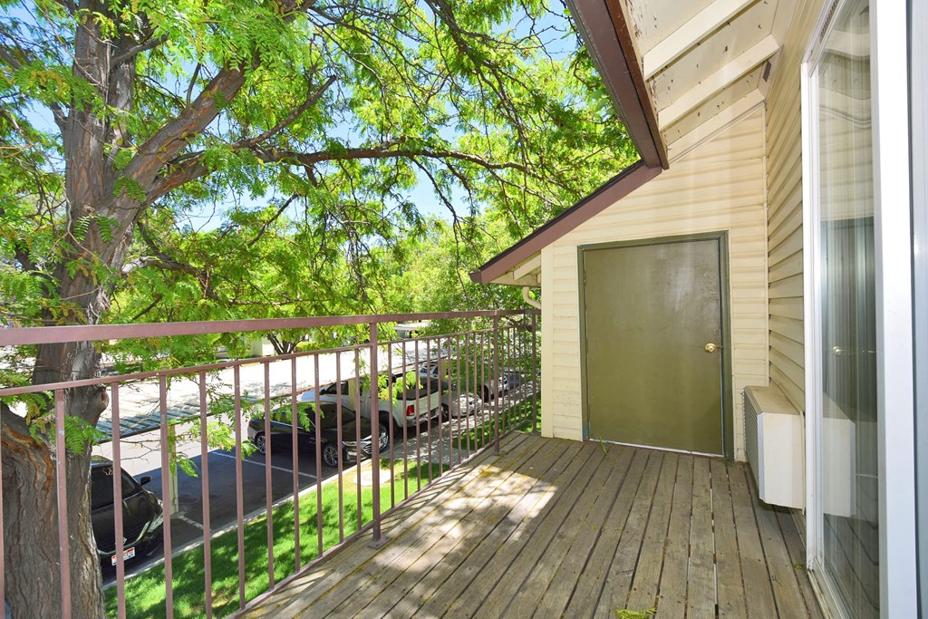 A balcony with a green door and a tree in front of a house.