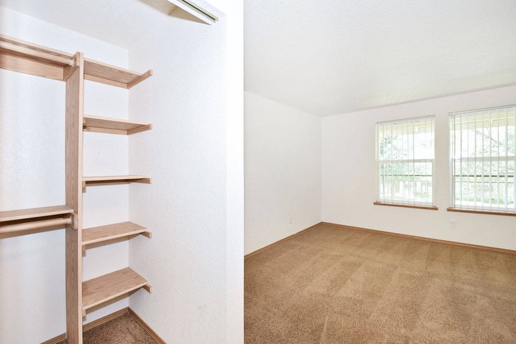 A room with a carpeted floor and a window with blinds.