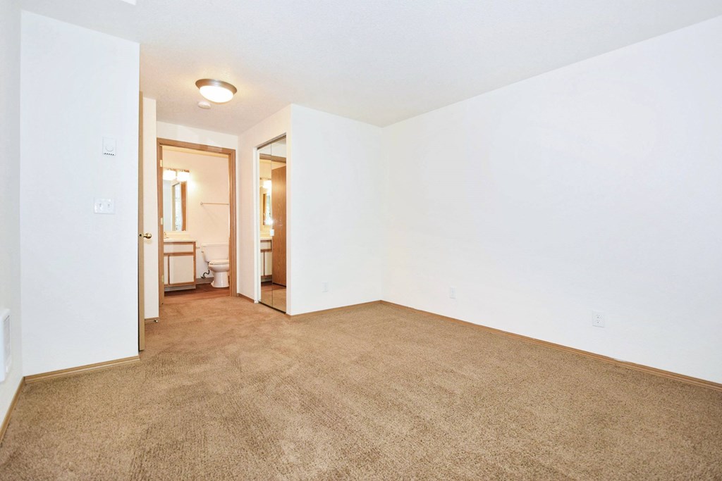 A room with a carpeted floor and a doorway leading to another room.