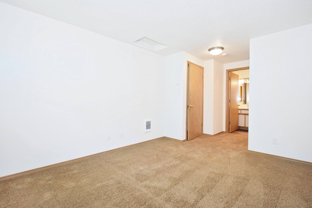 A room with a carpeted floor and a doorway leading to another room.