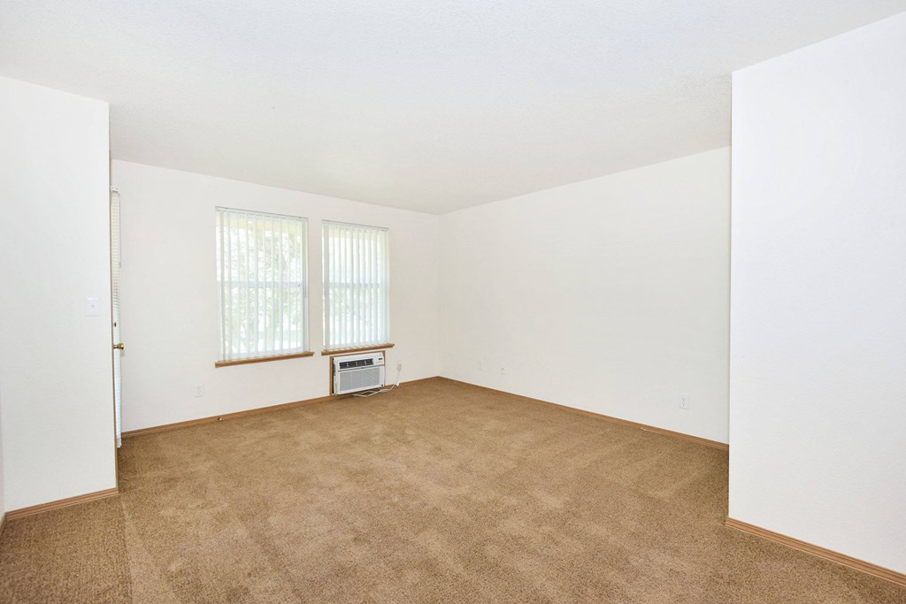 A room with a carpeted floor and a window with blinds.