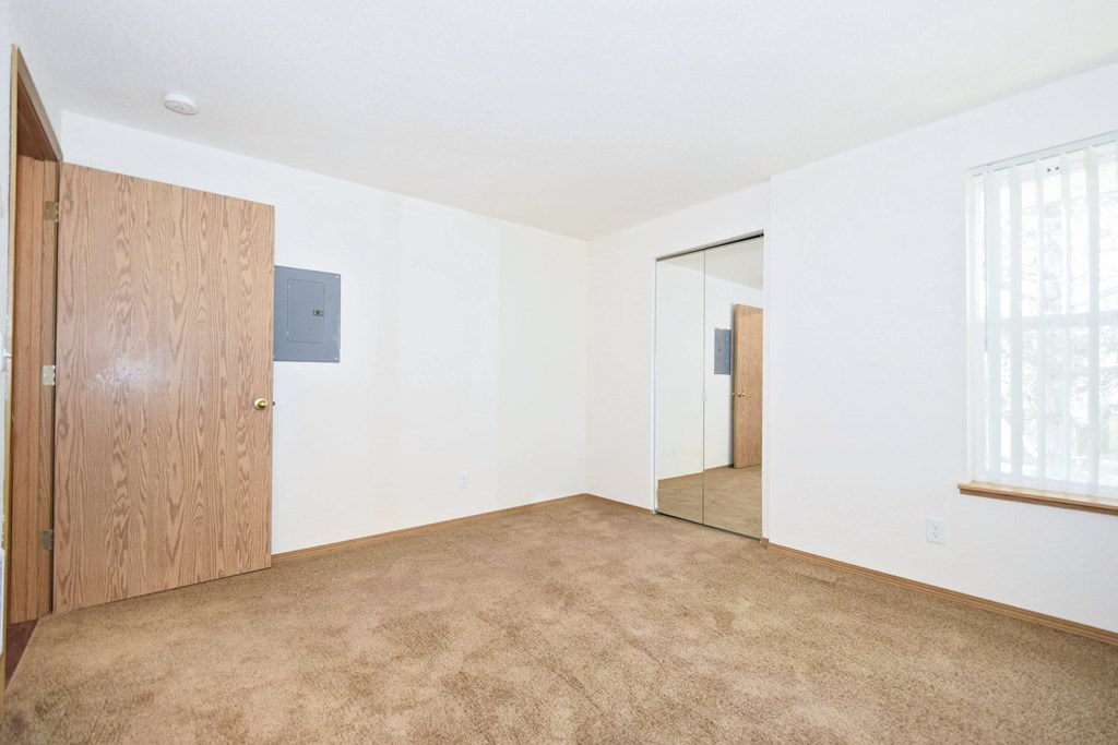 A room with a brown carpet and a wooden door.
